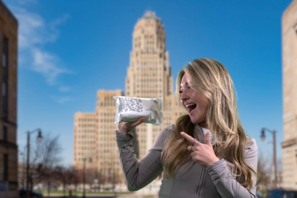 A photo of a woman pointing at a pack of Twipes truly flushable, truly biodegradable wet wipes in front of Buffalo City Hall